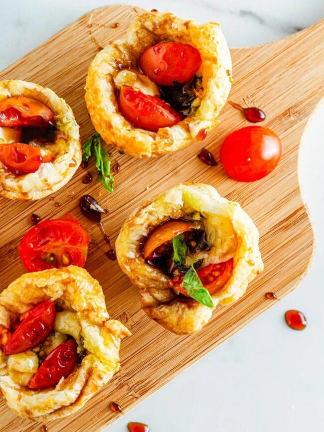 individual caprese salads in a pastry puff sitting on a cutting board