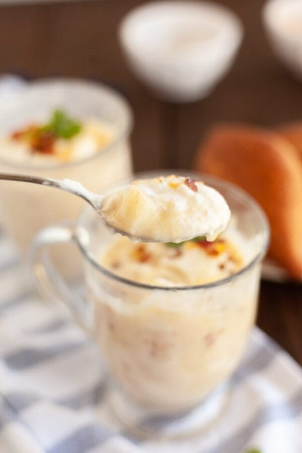 clear mug full of potato soup with a spoon