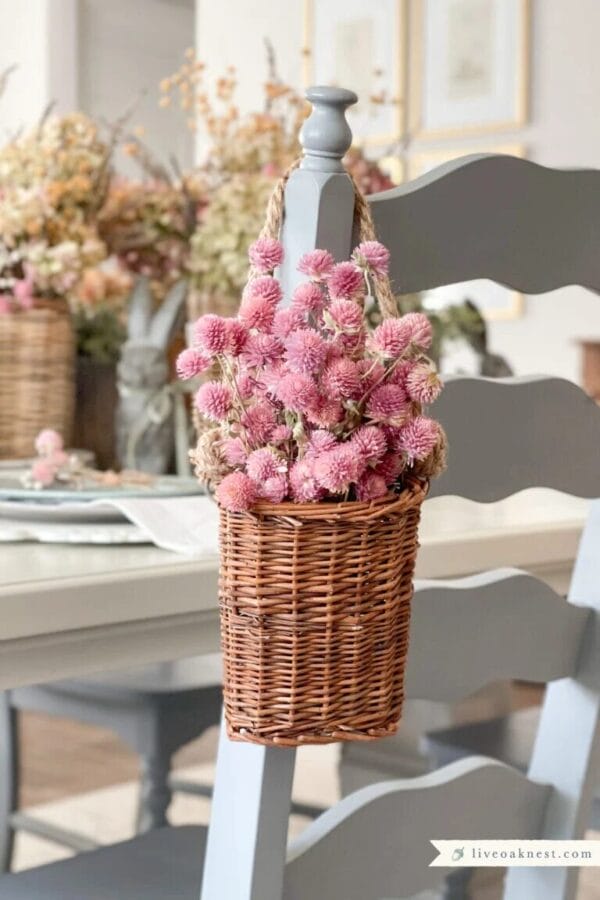 wicker basket of pink flowers hanging on the back of a dining chair