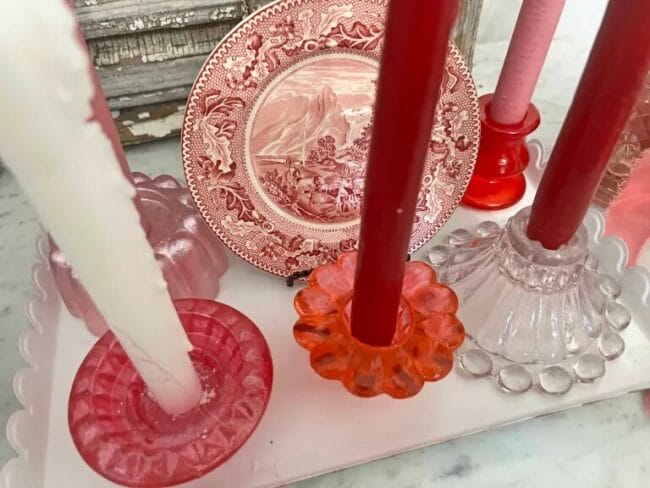 red and pink candle holders with candles and a pink and white transferware dish