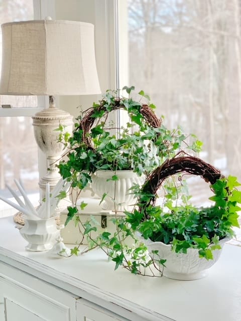 white bowls holding homemade wreath topiaries with a lamp and window in the background