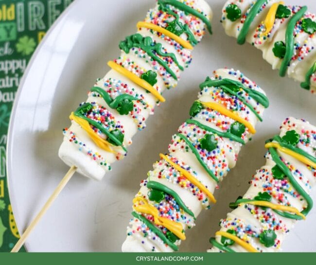 marshmallow stick treats with green and yellow sprinkles and little green shamrock candies on top.