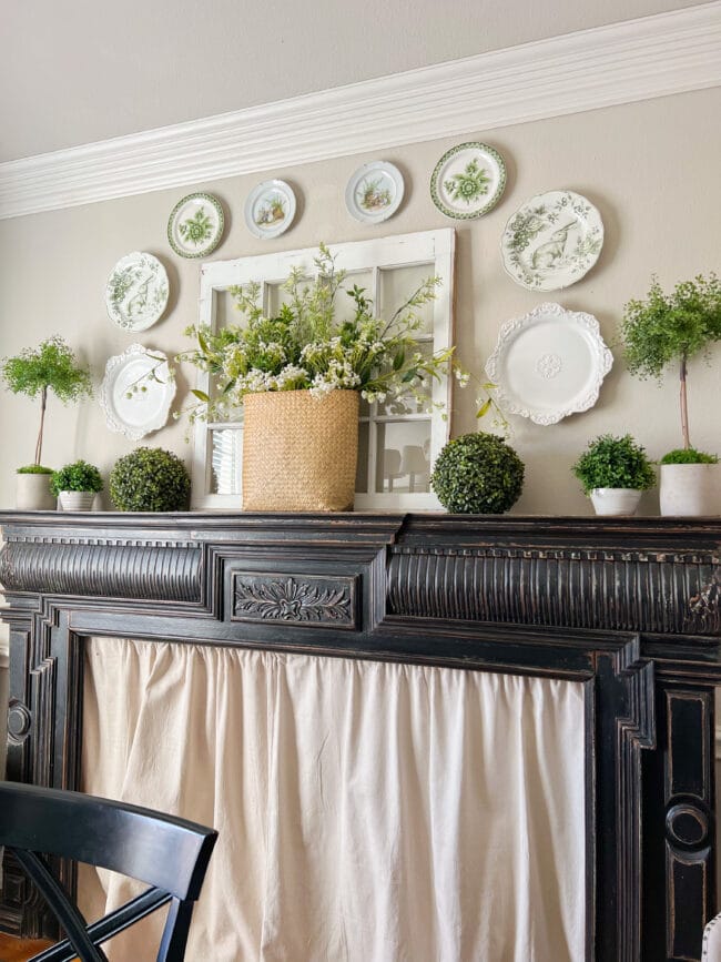 full black mantel with green and white spring plates hung around an antique window 