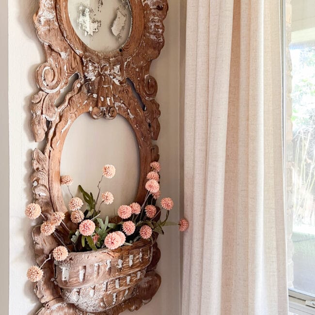 sq. of wooden antique mirror frame with pink pompom flowers and curtain in corner