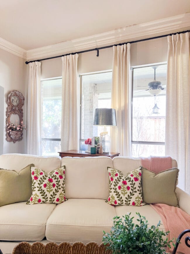 windows with curtains and full sofa with pink and green pillows