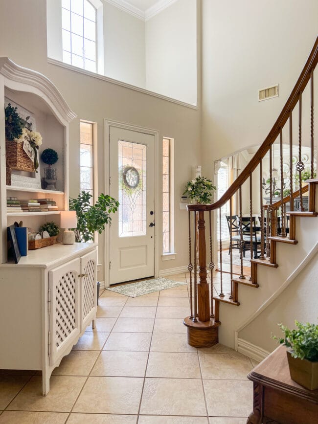 Full view of entryway with stairs and decorated white hutch