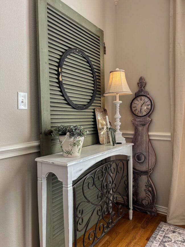 Vintage green screen door with white table, clock, lamp and floral arrangement