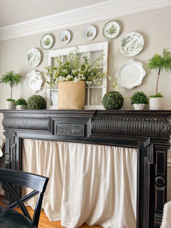 close up of black mantel with spring flowers and bunny plates