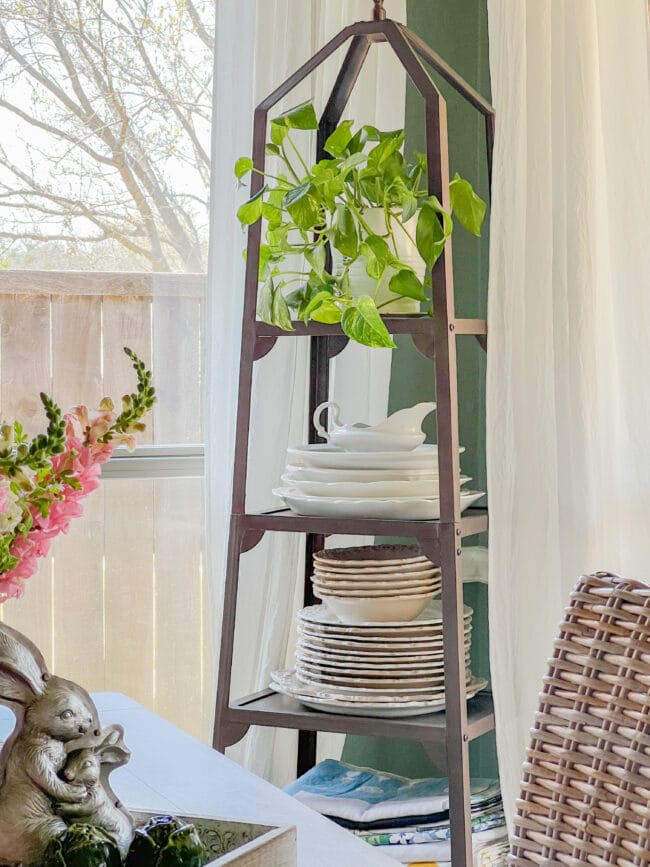 metal plate tower in front of window with plates and a plant on top