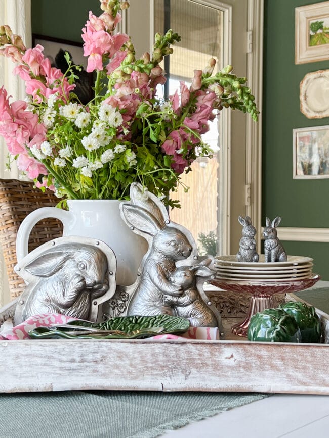 white tray with silver bunny molds, pink flowers. White dessert plates stacked with tiny bunnies on top.