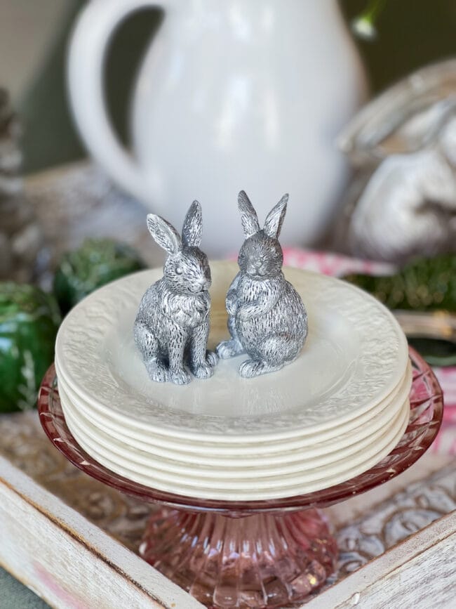 white dessert plates stacked with tivy silver bunnies on top.