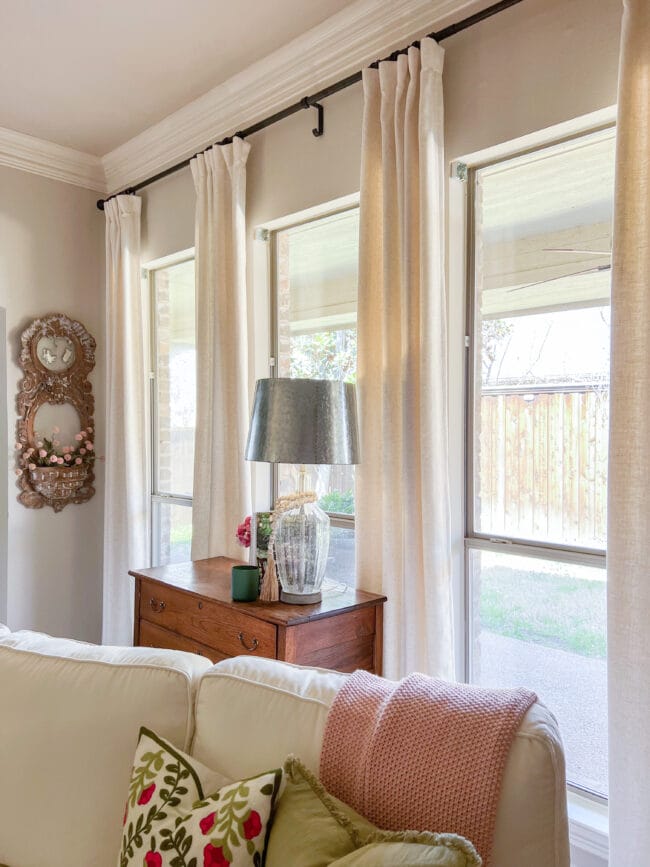 living room windows with antique hest, silver lamp and wooden mirror frame